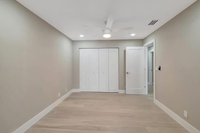 unfurnished bedroom featuring ceiling fan, a closet, and light wood-type flooring