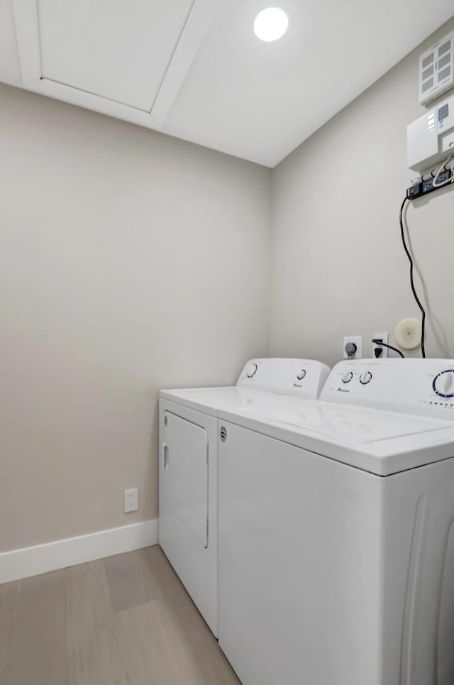 washroom featuring washing machine and dryer and light hardwood / wood-style flooring