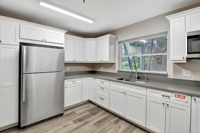 kitchen with white cabinets, stainless steel appliances, light hardwood / wood-style flooring, and sink