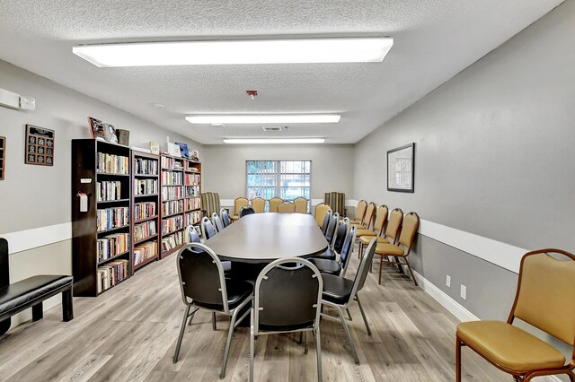 dining room with a textured ceiling and light hardwood / wood-style flooring