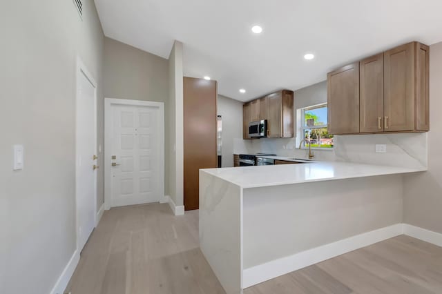 kitchen featuring kitchen peninsula, light hardwood / wood-style flooring, stainless steel appliances, and sink