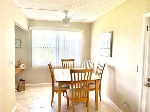 tiled dining room with a textured ceiling and ceiling fan