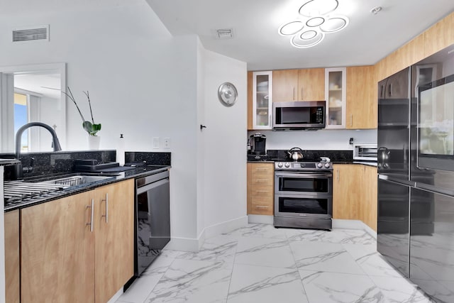 kitchen featuring sink, dark stone counters, and appliances with stainless steel finishes