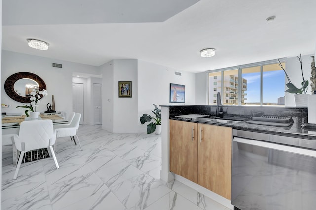 kitchen with stainless steel dishwasher, sink, and dark stone counters