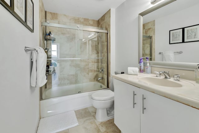 full bath featuring combined bath / shower with glass door, tile patterned floors, toilet, and vanity