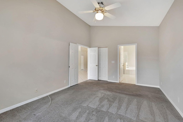 unfurnished bedroom featuring ceiling fan, carpet floors, ensuite bathroom, and high vaulted ceiling