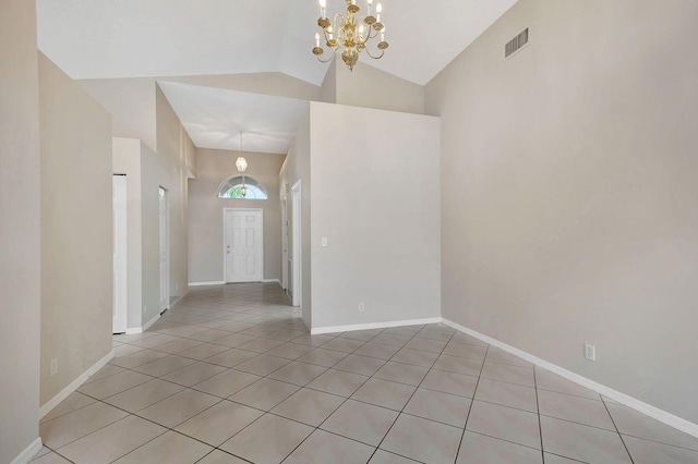 tiled spare room with high vaulted ceiling and an inviting chandelier