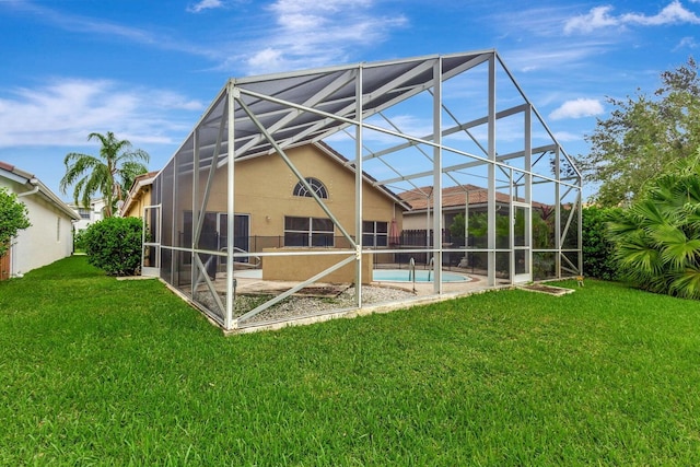 rear view of house featuring glass enclosure, a yard, and a patio