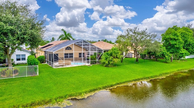 rear view of property with a lawn, a lanai, and a water view