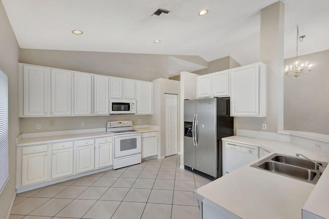 kitchen featuring lofted ceiling, white appliances, sink, a notable chandelier, and white cabinetry