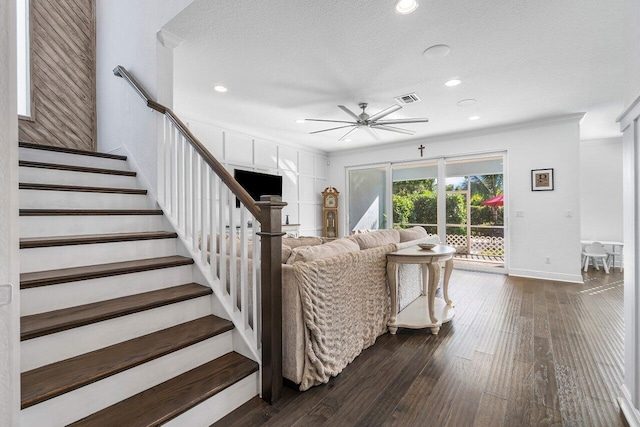 living room with dark hardwood / wood-style floors, ceiling fan, crown molding, and a textured ceiling