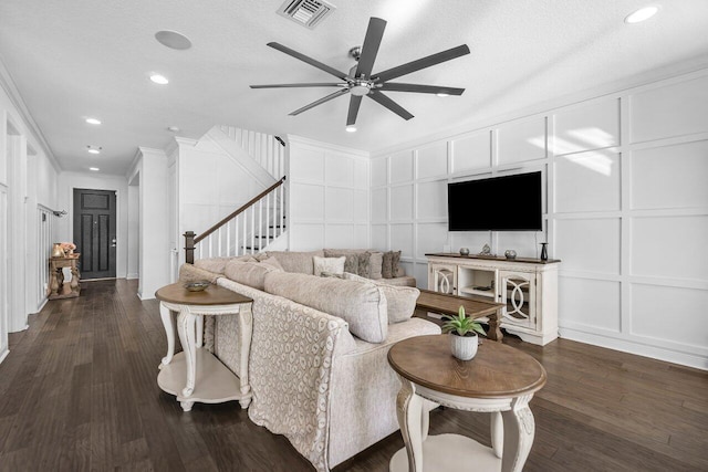 living room with a textured ceiling, ceiling fan, dark hardwood / wood-style floors, and ornamental molding