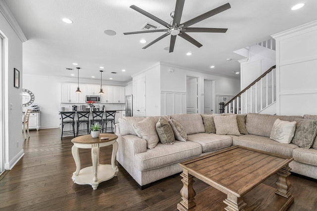 living room with a textured ceiling, dark hardwood / wood-style floors, ceiling fan, and crown molding