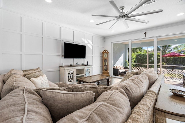 living room with ceiling fan, hardwood / wood-style floors, a textured ceiling, and ornamental molding