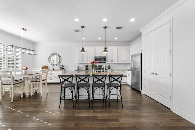 kitchen featuring decorative light fixtures, an island with sink, and appliances with stainless steel finishes