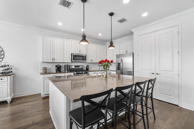 kitchen with white cabinets, dark hardwood / wood-style flooring, stainless steel appliances, and a center island with sink