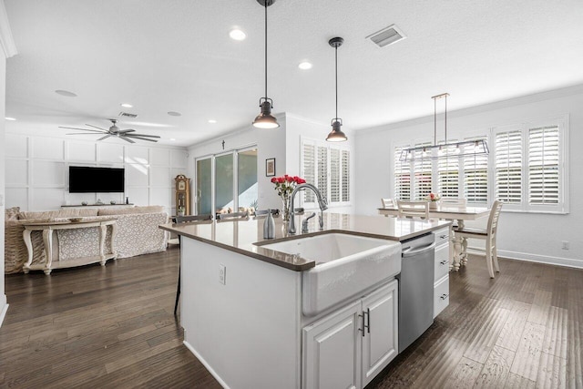 kitchen featuring white cabinetry, dishwasher, sink, decorative light fixtures, and a center island with sink