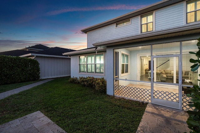 property exterior at dusk with a lawn