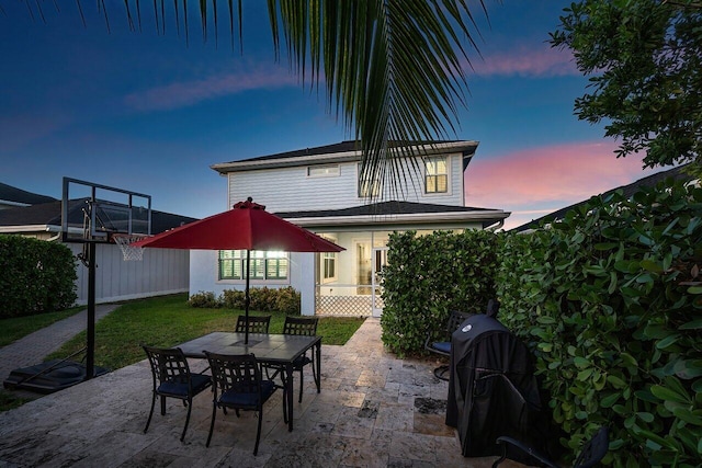 back house at dusk featuring a patio area and a yard