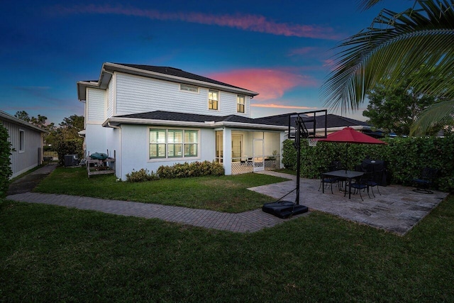 back house at dusk with a yard and a patio