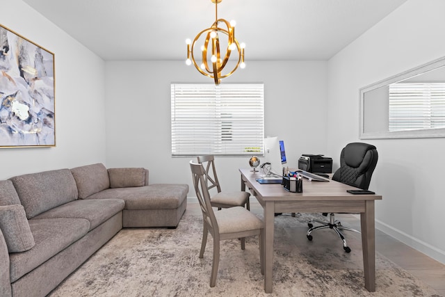 office with light wood-type flooring and an inviting chandelier