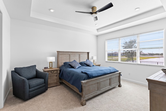 carpeted bedroom featuring ceiling fan and a tray ceiling