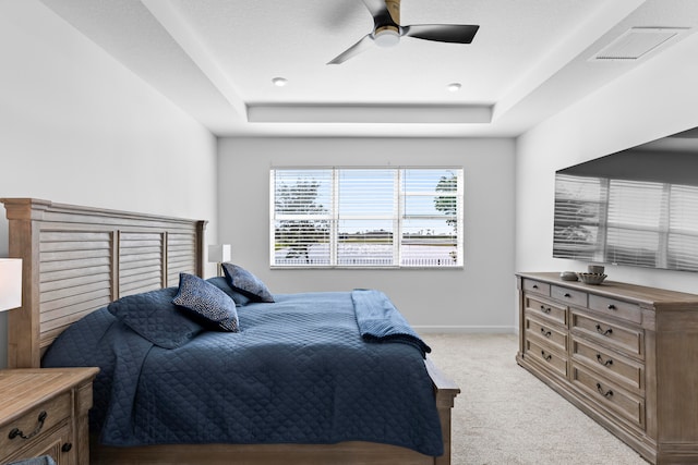 bedroom featuring a tray ceiling, ceiling fan, and light colored carpet