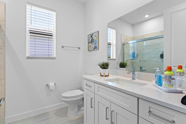 bathroom featuring vanity, hardwood / wood-style flooring, toilet, and a shower with door