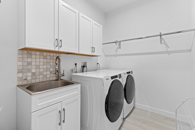 laundry area featuring sink, washer and clothes dryer, cabinets, and light hardwood / wood-style flooring