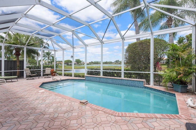 pool with a patio, a water view, and glass enclosure