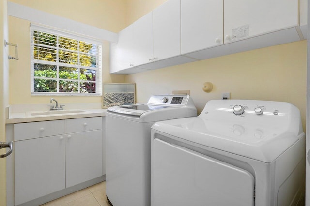 laundry room featuring cabinets, light tile patterned floors, washing machine and clothes dryer, and sink