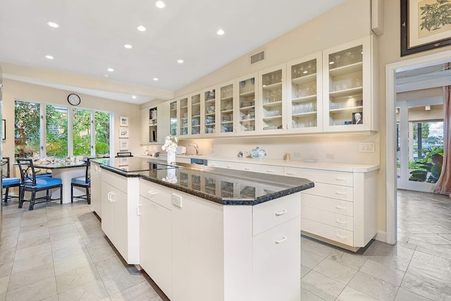 kitchen with a center island, lofted ceiling, dark stone counters, black electric stovetop, and white cabinetry