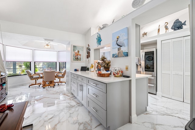 kitchen with gray cabinetry, ceiling fan, and stainless steel refrigerator with ice dispenser