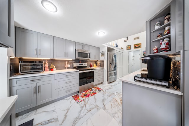 kitchen with appliances with stainless steel finishes, tasteful backsplash, and gray cabinetry