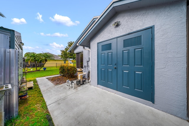 view of exterior entry with a patio and a lawn