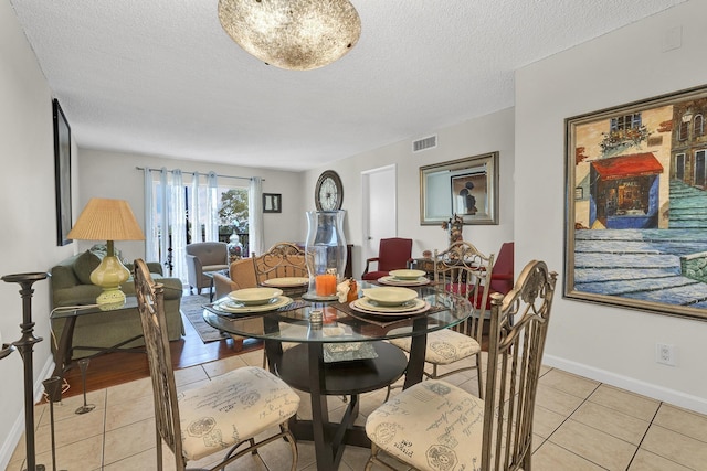 dining area with a textured ceiling and light tile patterned flooring