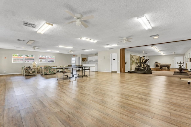 interior space with ceiling fan, a textured ceiling, and light wood-type flooring