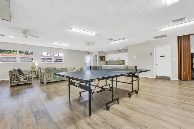 rec room with a textured ceiling, light wood-type flooring, and ceiling fan