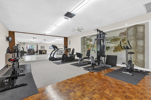 exercise room with parquet floors, a textured ceiling, and ceiling fan