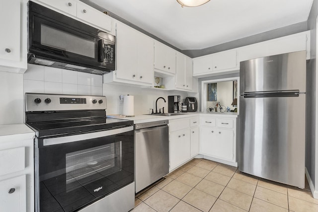 kitchen with appliances with stainless steel finishes, tasteful backsplash, sink, light tile patterned floors, and white cabinetry