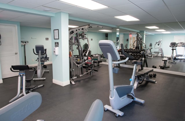 exercise room with baseboards and a drop ceiling