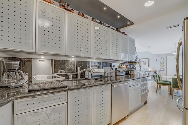 kitchen with dark stone counters, appliances with stainless steel finishes, a sink, and decorative backsplash