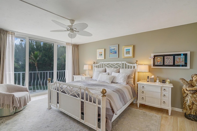 bedroom with a wall of windows, access to outside, a ceiling fan, and wood finished floors