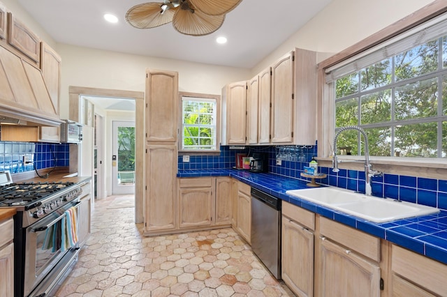 kitchen with a wealth of natural light, stainless steel appliances, tile counters, and sink