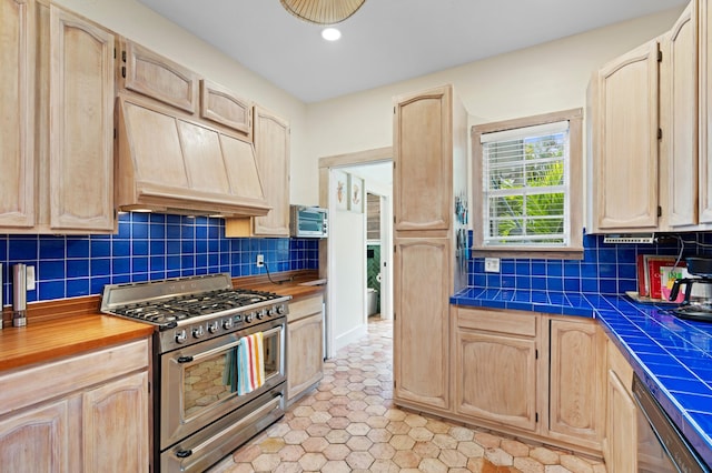 kitchen featuring tile counters, light brown cabinets, backsplash, and appliances with stainless steel finishes