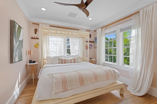 bedroom featuring ceiling fan, light hardwood / wood-style floors, ornamental molding, and multiple windows