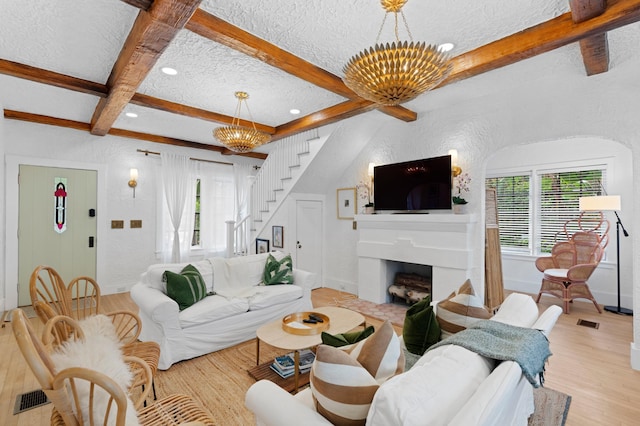 living room with beamed ceiling, light hardwood / wood-style floors, a textured ceiling, and a notable chandelier