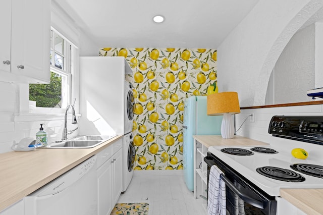 kitchen featuring stacked washer / dryer, white cabinetry, sink, and white appliances