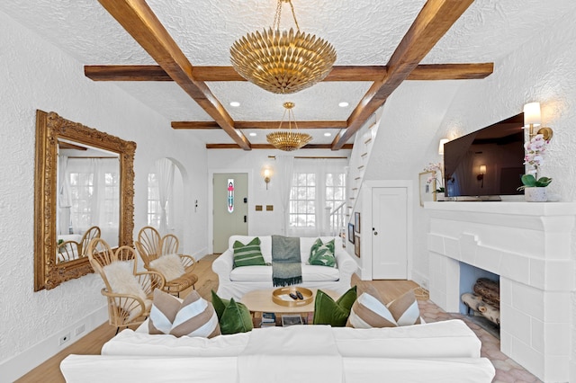 living room featuring a chandelier, beamed ceiling, light hardwood / wood-style floors, and a textured ceiling