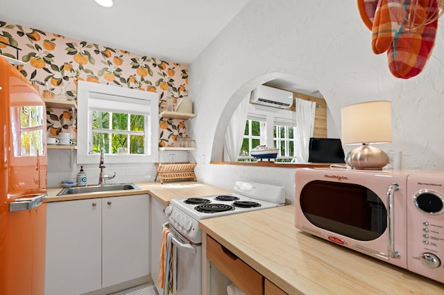 kitchen with a wall unit AC, white cabinetry, plenty of natural light, and white electric range